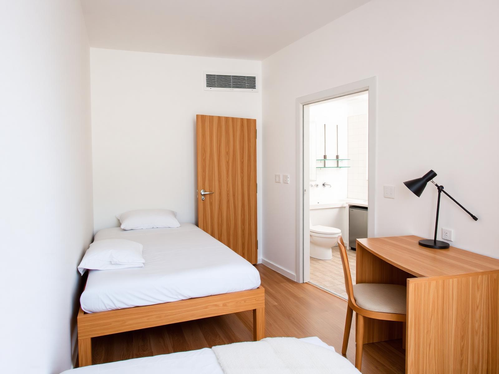 Habitación individual con baño privado en suite, escritorio de madera y aire acondicionado